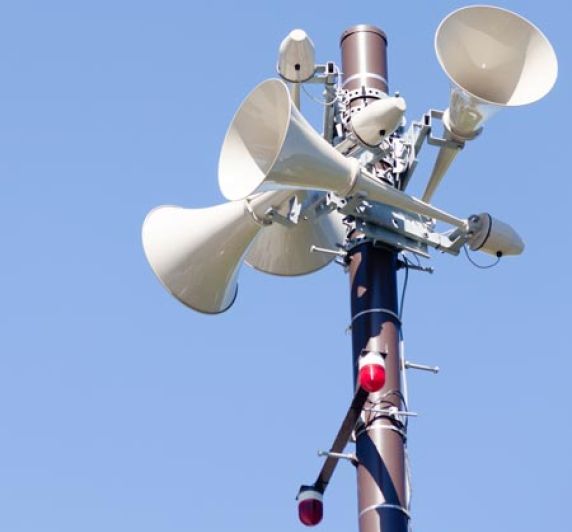 outdoor emergency siren against blue sky