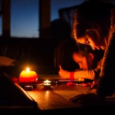 two little girls draw on a table with a candle during a power outage