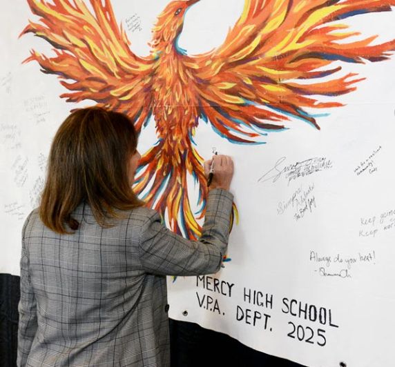 staff signing Wildfire Ready event poster of an orange Phoenix bird