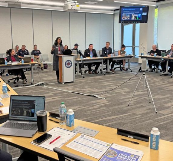 Emergency Services Council meeting with officials discussing emergency management governance in a conference room